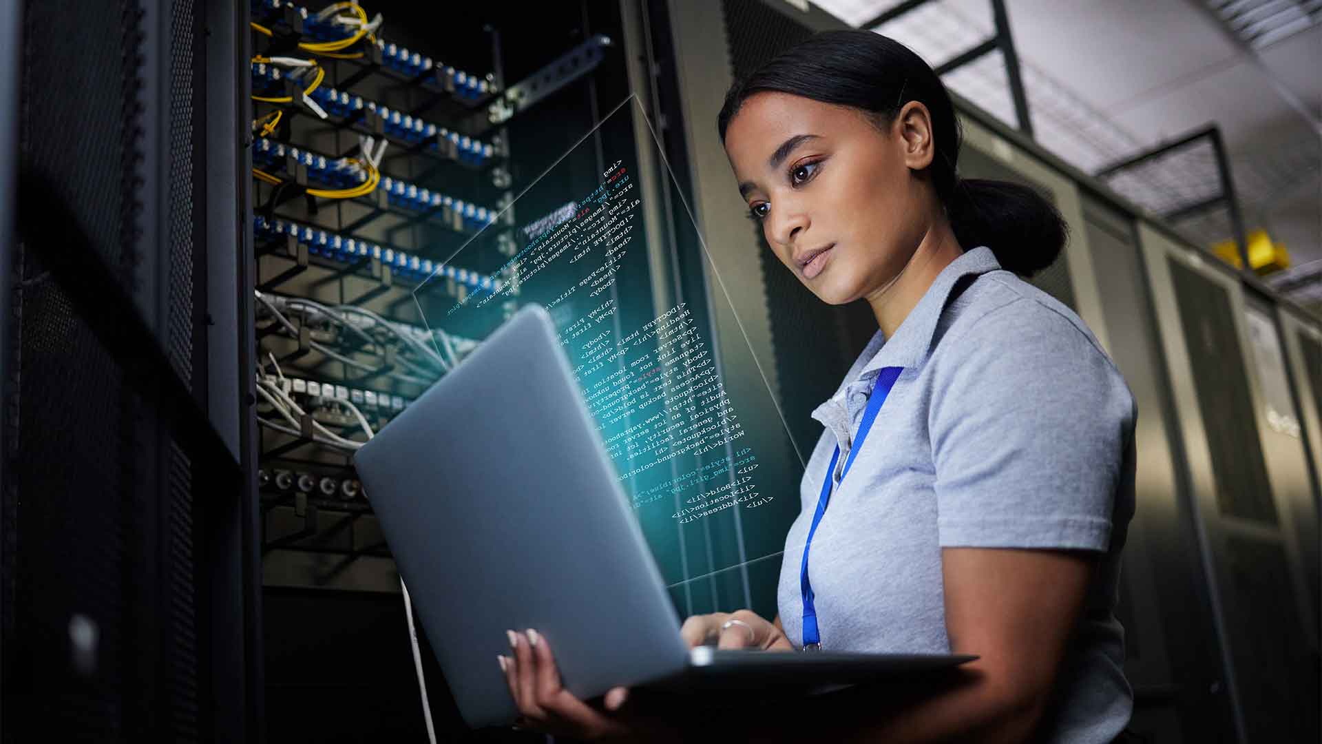 Female cyber security professional searches for information on laptop next to an open server box.